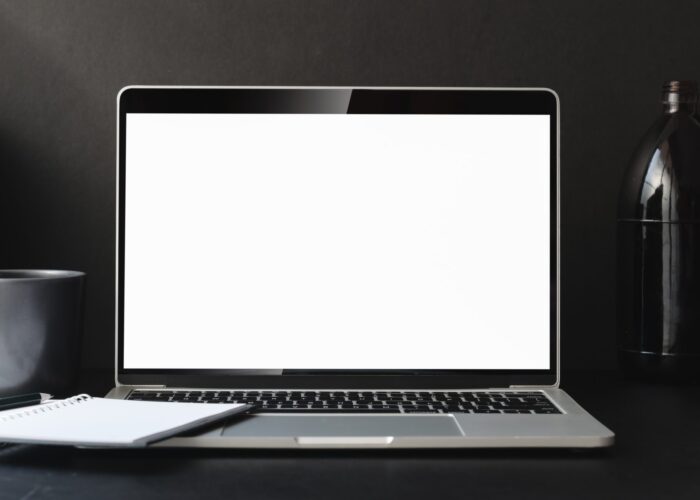 Open blank screen laptop computer in dark modern office room with office supplies and decorations